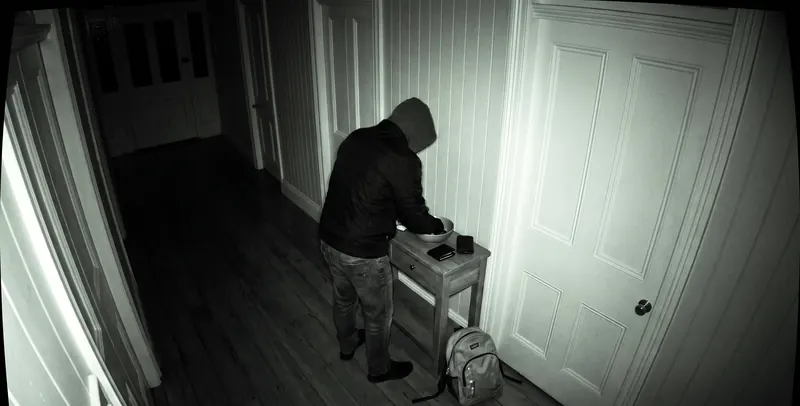 A hooded figure going through a bowl on a hall table while the bedroom doors stay shut